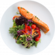 Filete de salmón fresco servido sobre una cama de ensalada variada con lechuga, tomates cherry y tiras de zanahoria. Ideal para una comida saludable.