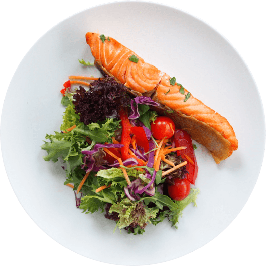 Filete de salmón fresco servido sobre una cama de ensalada variada con lechuga, tomates cherry y tiras de zanahoria. Ideal para una comida saludable.