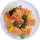 Plato de sashimi de salmón fresco, presentado en una bandeja blanca con rodajas de limón, decoraciones de lechuga y perejil, acompañado de huevas de salmón y encurtidos. Ideal para amantes de la cocina japonesa.