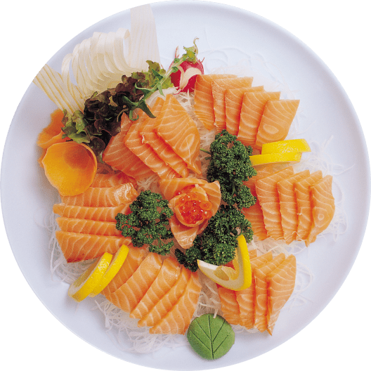 Plato de sashimi de salmón fresco, presentado en una bandeja blanca con rodajas de limón, decoraciones de lechuga y perejil, acompañado de huevas de salmón y encurtidos. Ideal para amantes de la cocina japonesa.