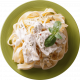 Plato de fettuccine con salsa cremosa, decorado con hojas de albahaca fresca y espolvoreado con hierbas. Ideal para amantes de la pasta.